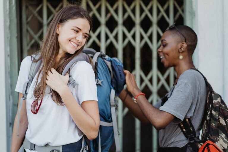 Two women smiling and enjoying a travel adventure while backpacking outdoors.